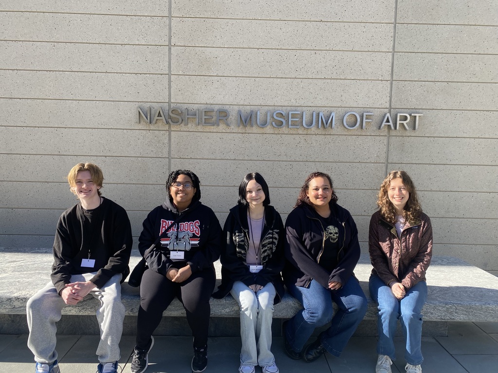 5 high school students (1 male and 4 females) sitting on a bench with Nasher Museum of Art behind them.