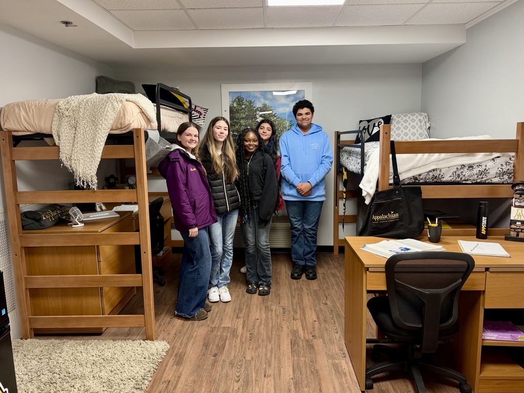 A small group of students posing in an example dorm room