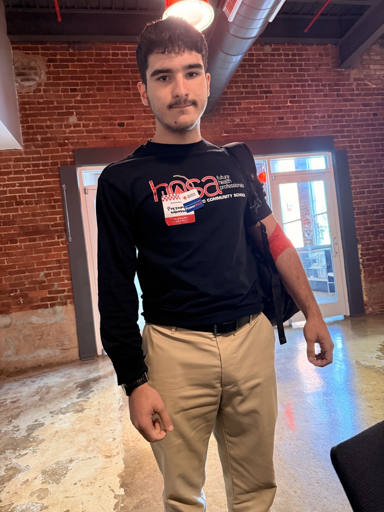 A male student in a black t-shirt with a red blood drive bandage on his left arm.