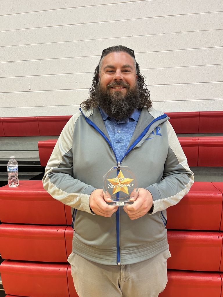 Mr. Baskerville smiling while holding a clear trophy with a star on it that says Star Performer