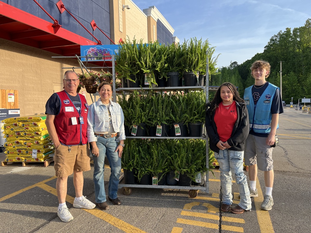 Two Lowes workers and Mrs. Miller and Kendyll miller standing in the Lowes parking lot with a cart full of ferns.