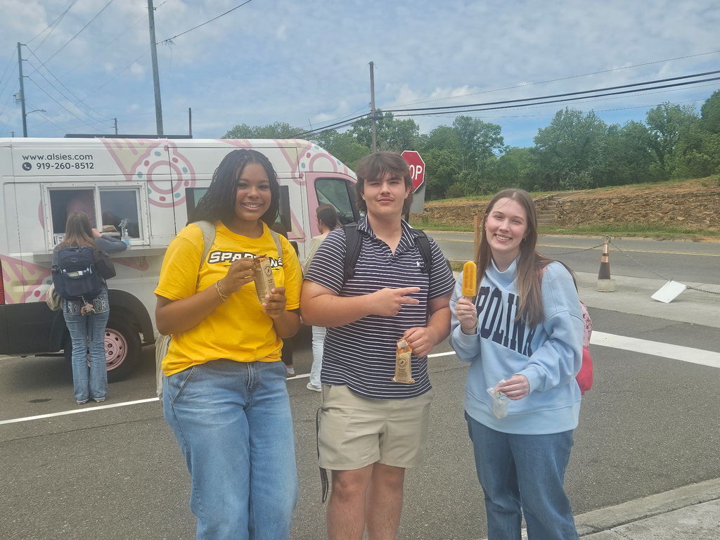 Three high school students posing holding popsicles