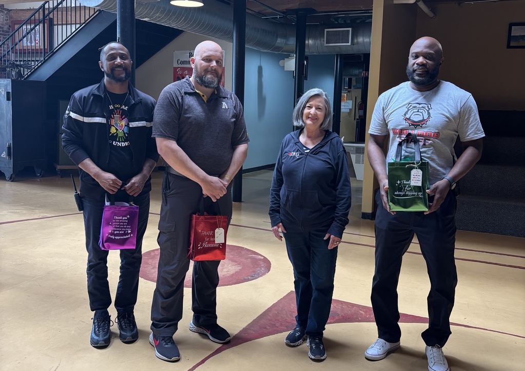 From left to right, Jamel Jones, Jeremy Martin, Deborah E. Burke, and Darkarai Bryant standing in the RCS lobby. The men are holding gift bags.