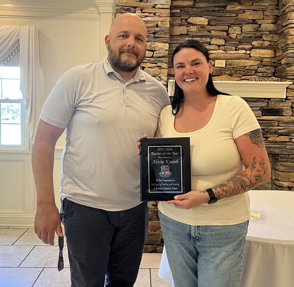Jeremy Martin (Left) and Alecia Knaub (right) smiling while Alecia holds a plaque for the 2025-2026 Teacher of the Year