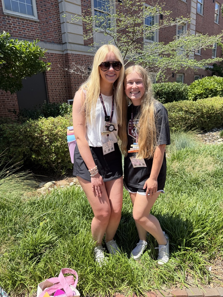 Two blonde teenage girls, Riley Young and Mary Alice Grissom smiling outside a building, standing in grass.