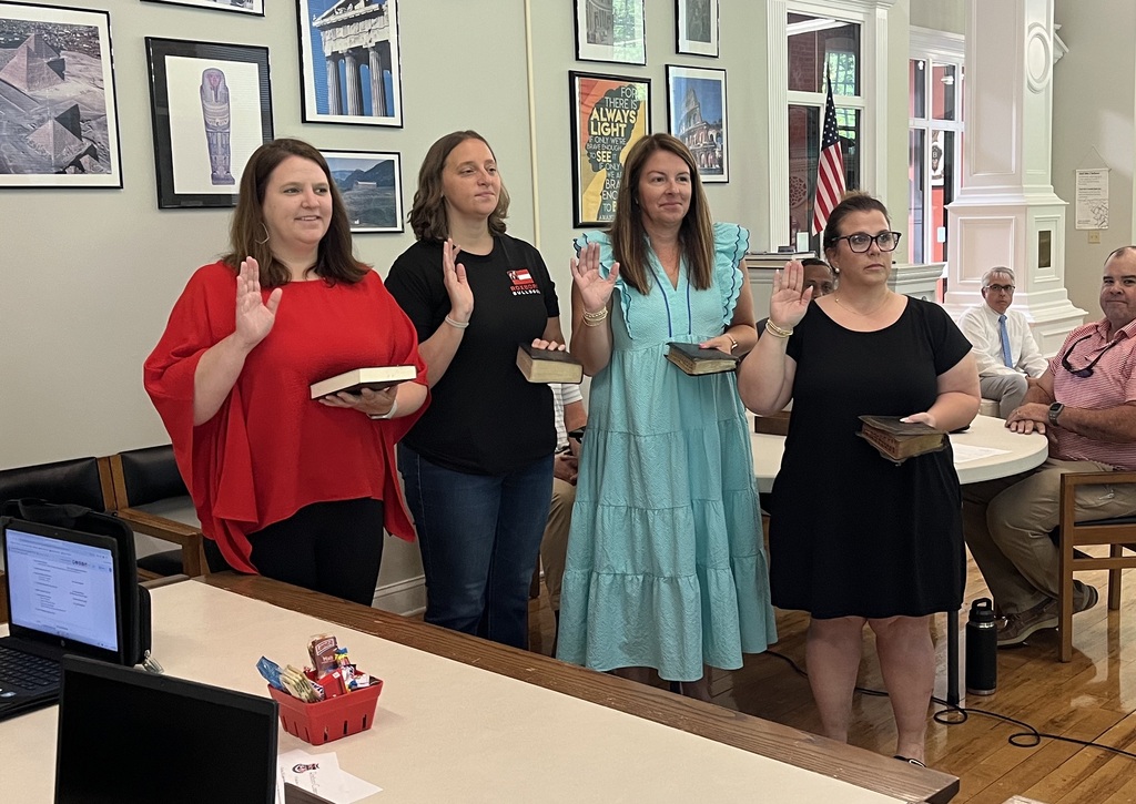 From left to right, Jenny Eggleston, Jennifer Brown, Laura Atkins, and Jona Fitzgerald, all holding a Bible with their right hand raised, taking the oath of office. 