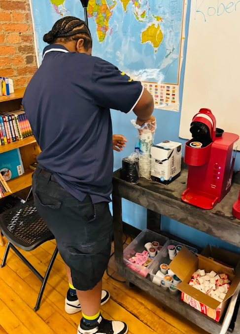 Student grabbing a cup to make a coffee with a  keurig.