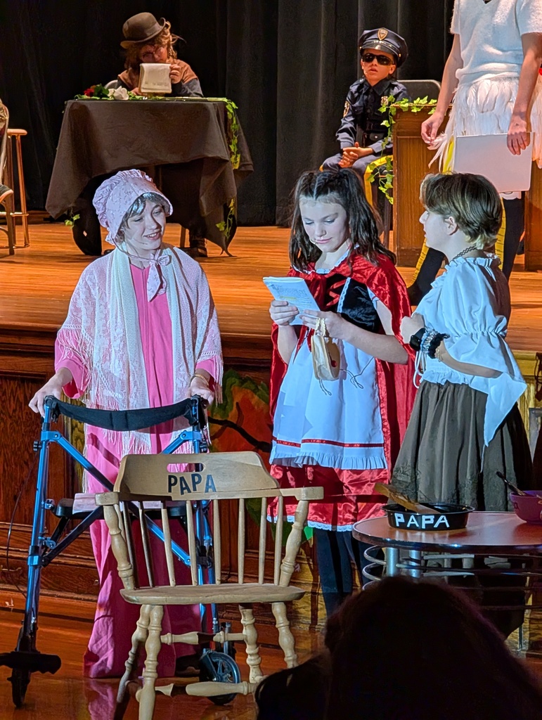 Students on stage in their little red riding hood and her grandma costumes for the play Once Upon a Crime