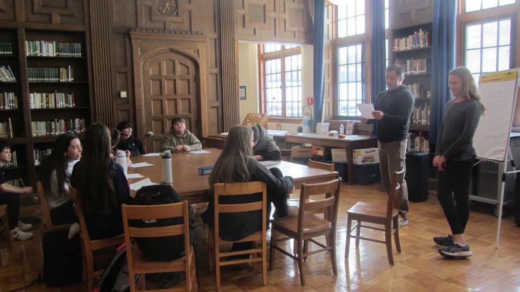 Pablo Cartaya hosting a workshop with middle school students sitting at a table in a library 