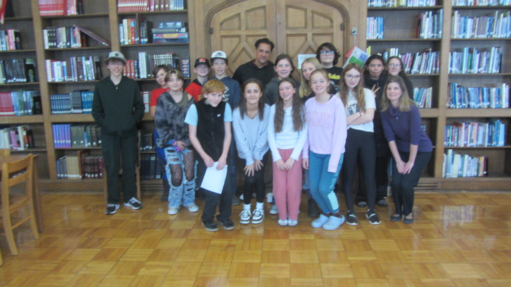 Pablo Cartaya posing for a picture with middle school students in a library