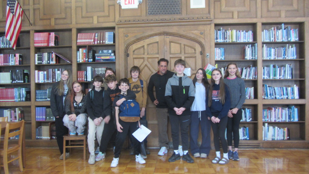 Pablo Cartaya posing for a picture with middle school students in a library