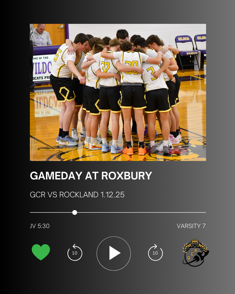 The image shows a group of high school boys basketball players wearing white jerseys with black and gold trim standing in a tight huddle at center court of a gymnasium. Their arms are around each other’s shoulders, forming a circle as they prepare for the game. The polished wooden gym floor and team logo are visible beneath them. Below the photo, the graphic is styled like a music player screen and includes text that reads “Gameday at Roxbury,” “GCR vs Rockland,” and the date. Additional text shows game times: JV at 5:30 and Varsity at 7:00. A GCR logo appears in the corner, reinforcing the school spirit and game-day theme.