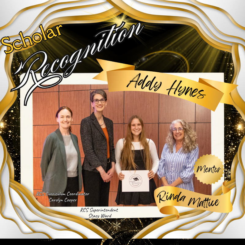 A formal, celebratory scholar recognition poster designed in black, gold, and white honors Addy Hynes. The background features shimmering gold sparkles, sweeping ribbon-like gold borders, and dramatic light effects for an elegant awards-style appearance. Across the top, stylized script and bold lettering read “Scholar Recognition,” with decorative gold flourishes framing the title.  At the center is a large framed group photo showing four women standing side by side in front of a wood-paneled wall. From left to right: Carolyn Cooper, identified as RCS Curriculum Coordinator, wears a muted green blazer over professional attire; Stacy Ward, RCS Superintendent, stands next in a dark blazer with an orange blouse; Addy Hynes, the honoree, stands smiling in the center holding a certificate while wearing a black and white dress; and mentor Rinda Mattice stands on the far right in a light blue striped dress.  A gold ribbon banner near the top right prominently displays Addy Hynes’ name, while another gold ribbon near the lower right identifies Rinda Mattice as Mentor. Carolyn Cooper and Stacy Ward’s names and titles are displayed near their positions in smaller text. The overall composition resembles an upscale academic awards announcement, emphasizing achievement, mentorship, and celebration.