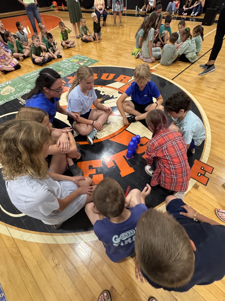 blue team members circled around a stack of cups to compete in a board game event