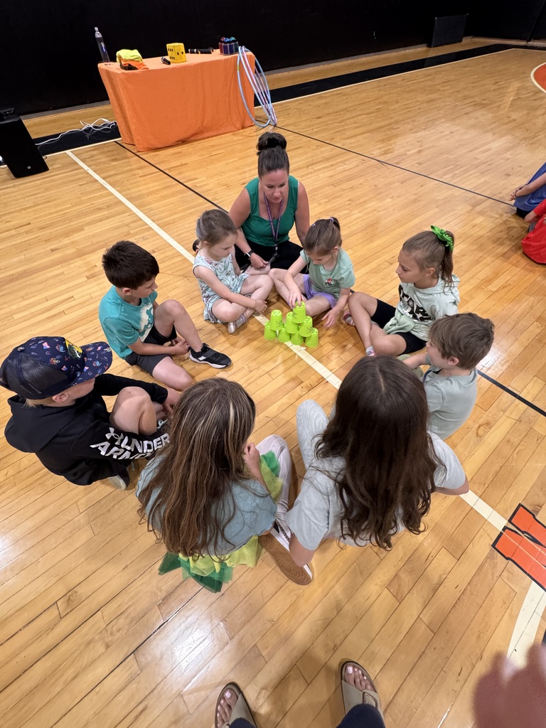 green team members circle around a stack of cups to compete in a board game event