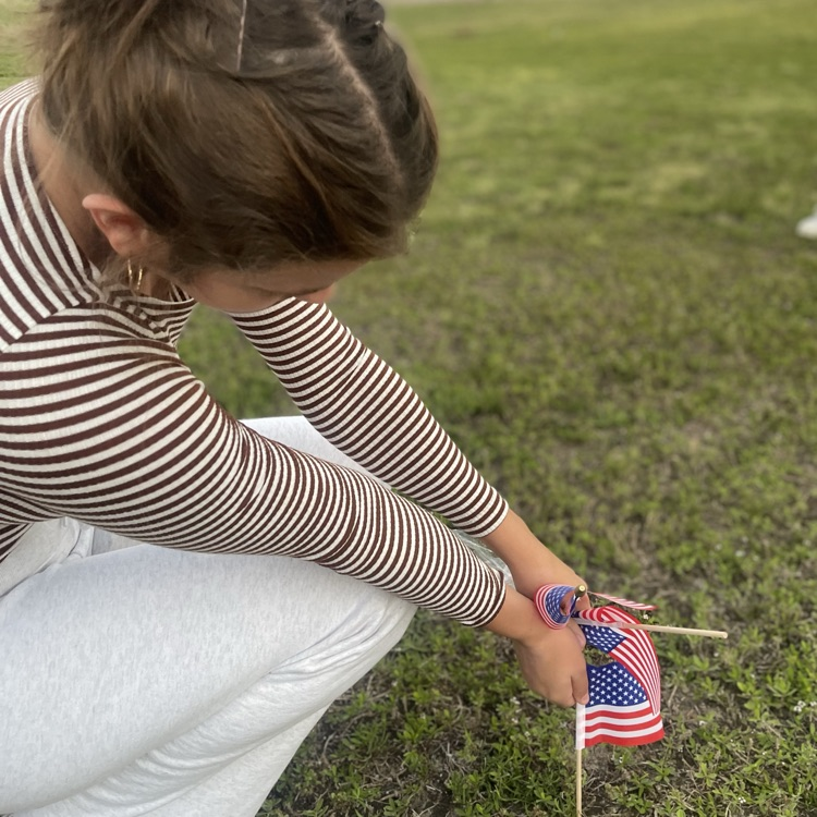 Student joins in to help place flags on campus