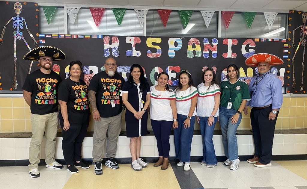 Spanish team stands in front of Hispanic Heritage Month banner.