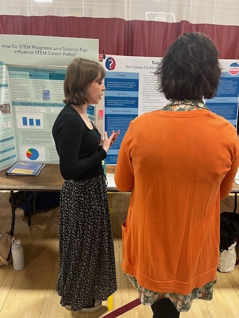 Amber Haining describes her project to a judge at the Maine State Science Fair. 