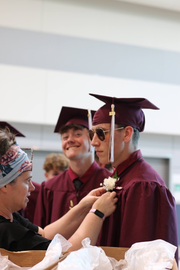 Ms. Coppa pins a boutonnière on Brady Sawyer, with Hunter Goodblood  smiling in the background.  