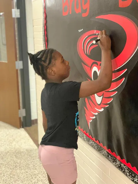Student signing brag board 