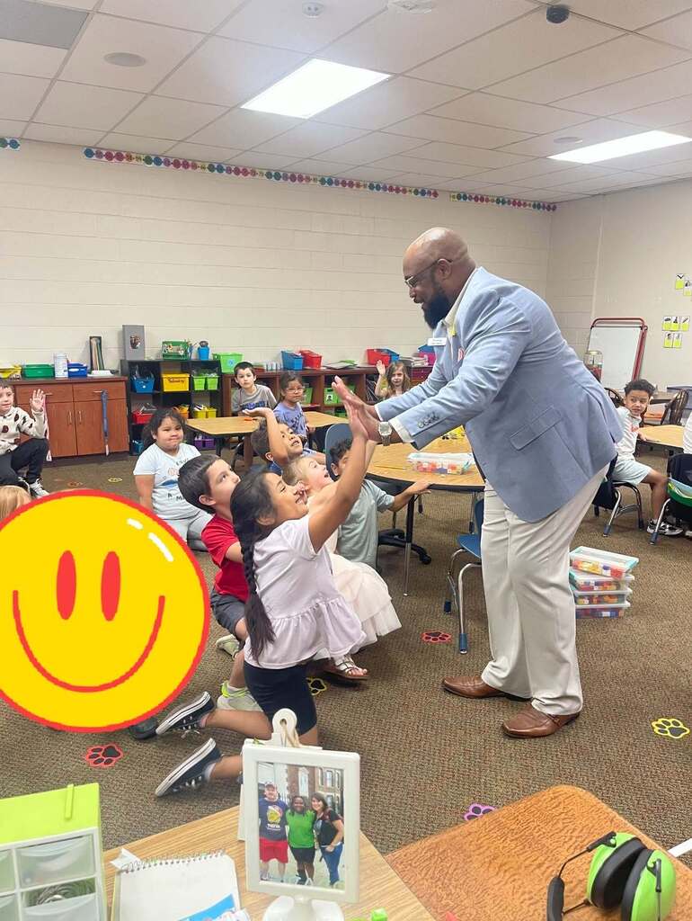 man giving high fives to students in a classroom