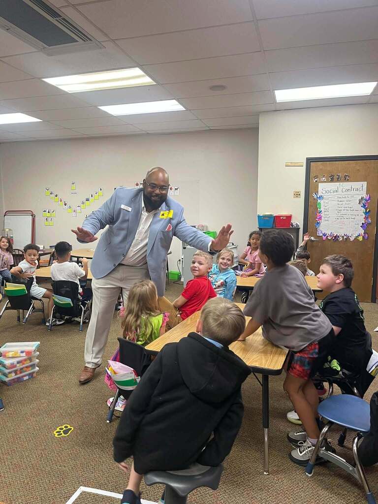 man giving high fives to students in a classroom