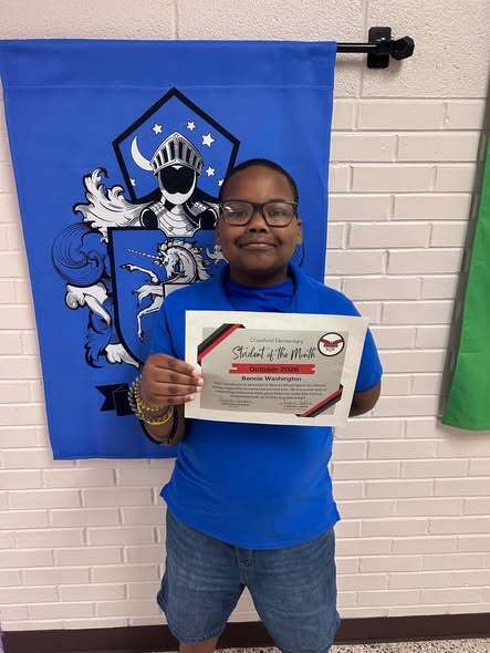 boy standing with student of the month certificate