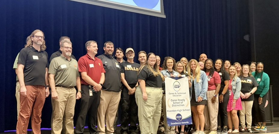teachers from riverdale high pose with banner for career & technical education excellence