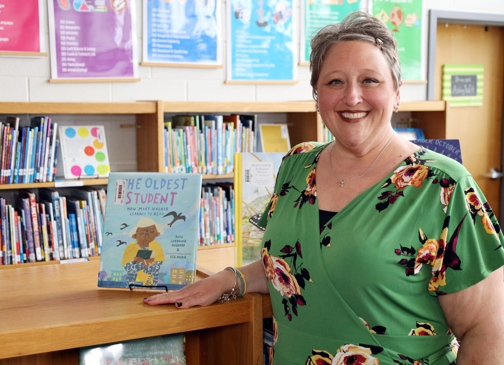 Woman stands in school library in green dress