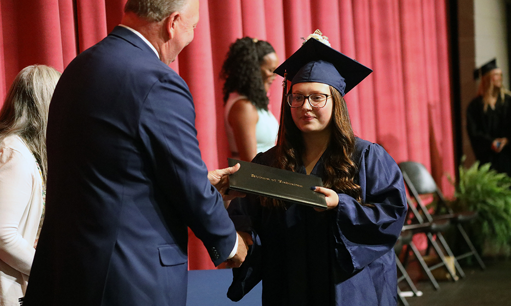 Summer graduation a student receives her diploma