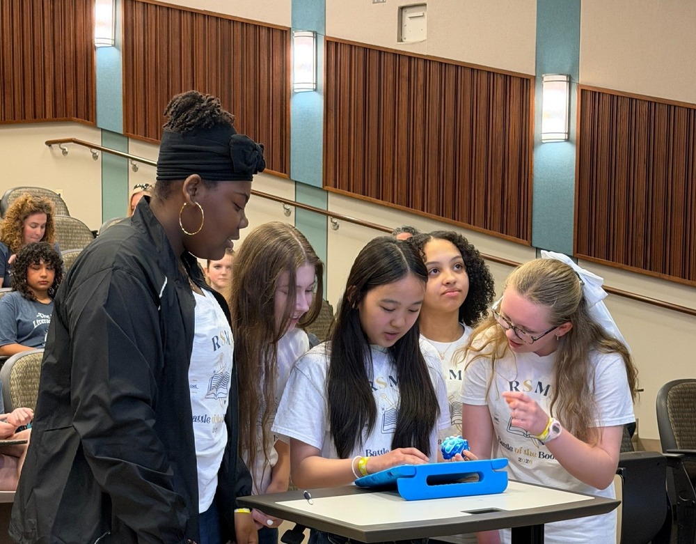 Four RSMS students look at an ipad in the Battle of the Books competition