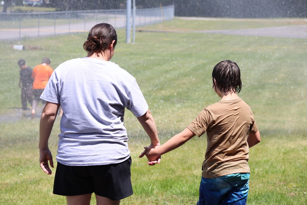 Woman and student hold hands and prepare to run into sprinklers