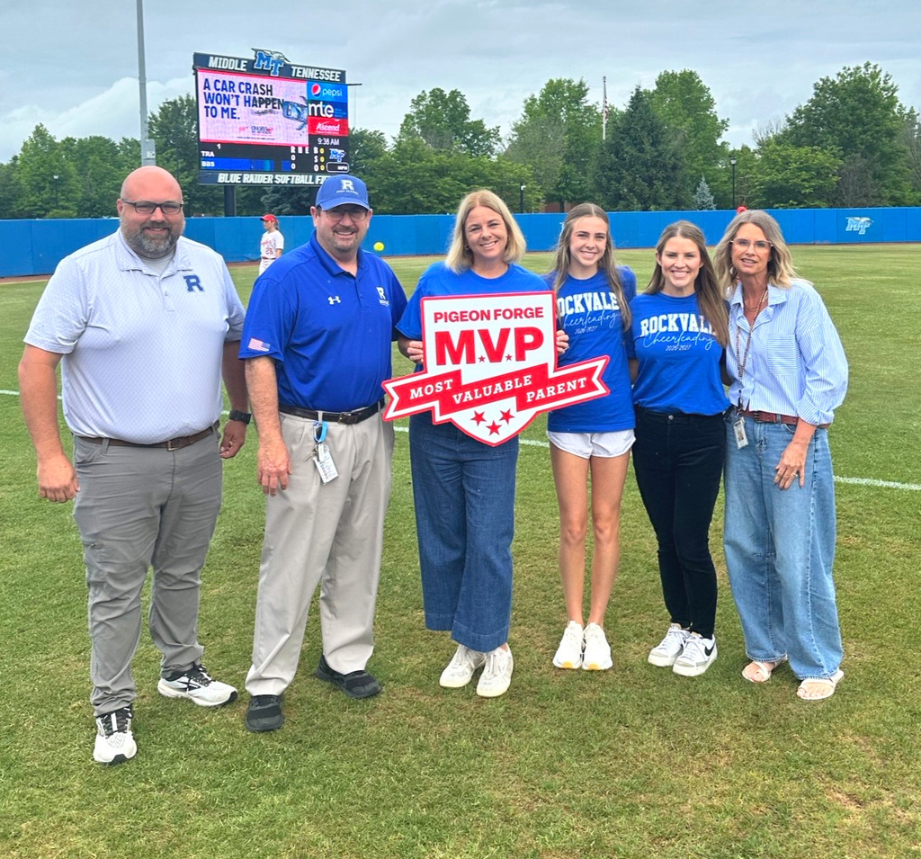 Group of six people smiling for picture in front of Softball field, holding sign that reads, "Pigeon Forge, M.V.P, Most Valuable Parent."