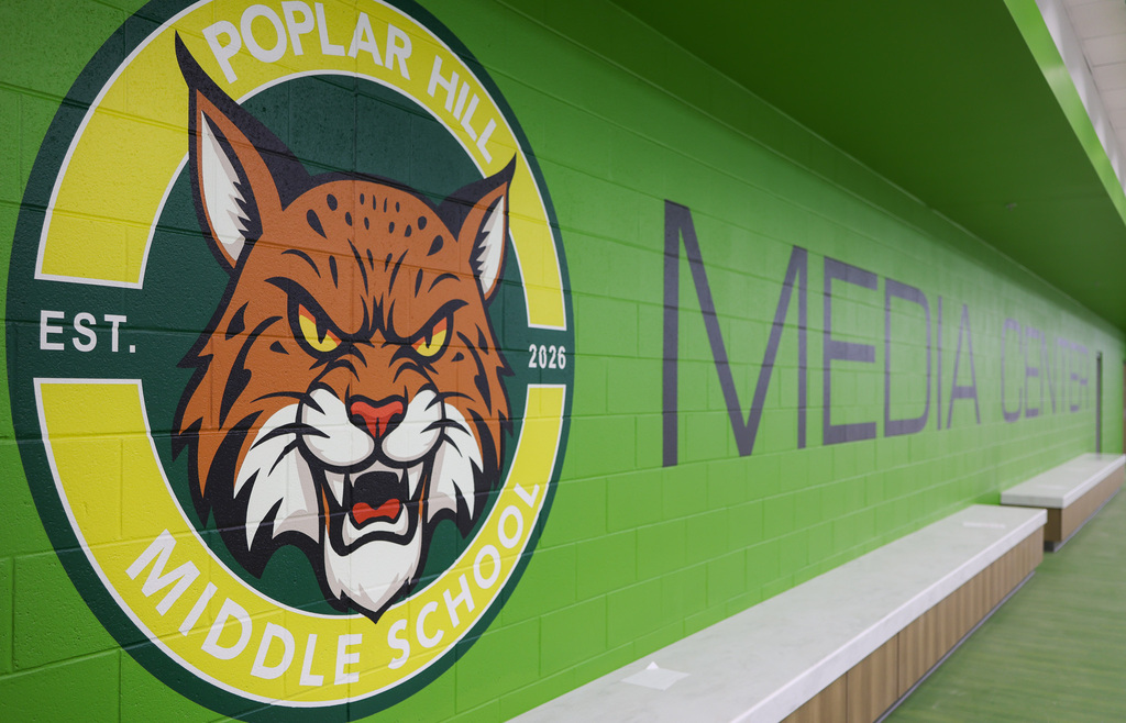 A green wall displays the "Poplar Hill Middle School" logo with a fierce lynx and the words "Est. 2015".