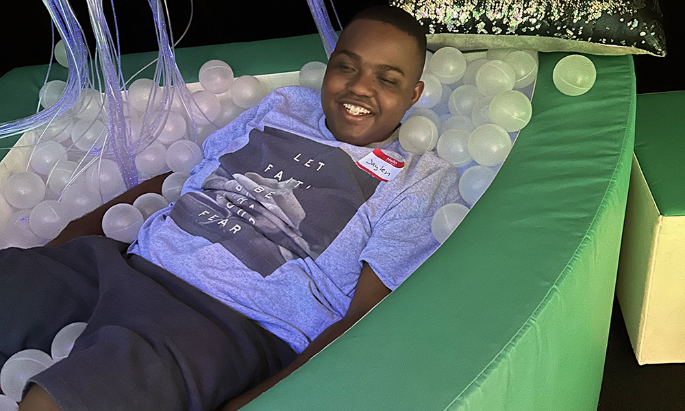 Person lying in a cushioned ball pit wearing a shirt with a graphic on it.