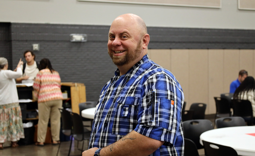 A man in a blue and black shirt smiles