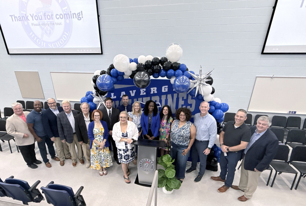 A group of people in formal attire pose behind a podium and balloons with text "LaVergne Athletics."