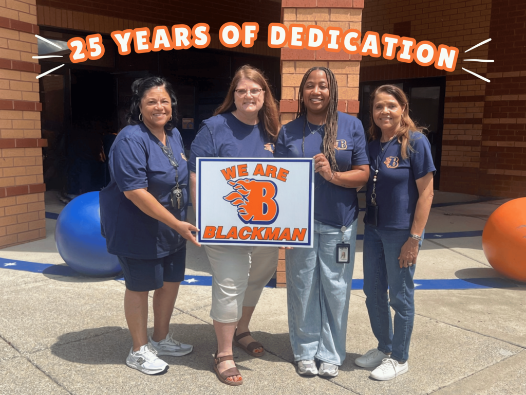 Four women stand in front of a building, holding a sign that says "We are Blackman." They wear matching blue shirts.