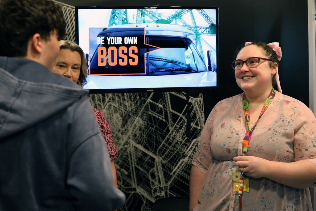 Teacher smiles at student with words "be your own boss" on screen 