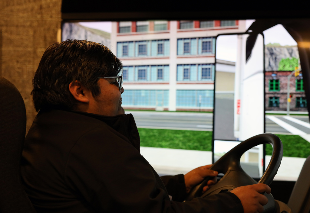 male student with glasses operates 18-wheeler simulator