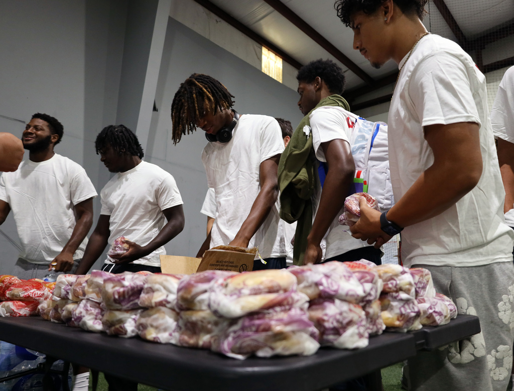 Football players in white shirts grab biscuits from a table