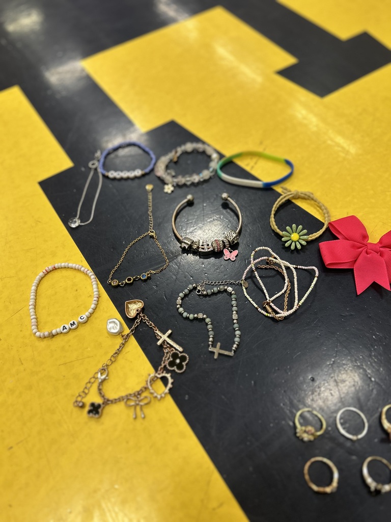 Various bracelets and rings displayed on a black surface with a yellow background. The collection includes silver and gold pieces, with some featuring decorative elements.