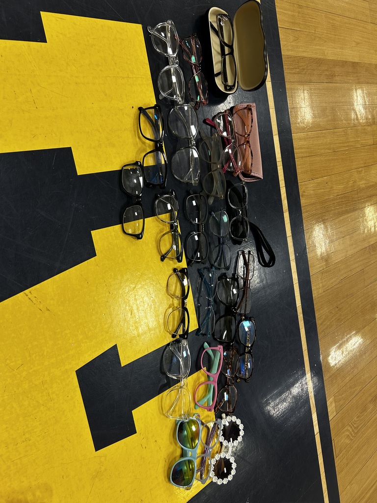 Various eyeglass frames, cases, and sunglasses are arranged on a yellow and black background.