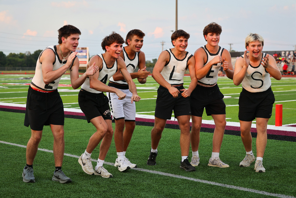 Five young athletes wearing matching uniforms pose for a photo on a football field.