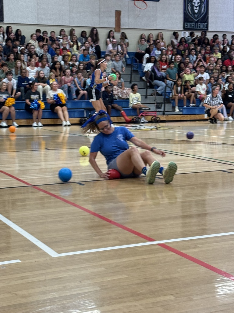 An indoor basketball court with a player on the ground in front of a crowd.