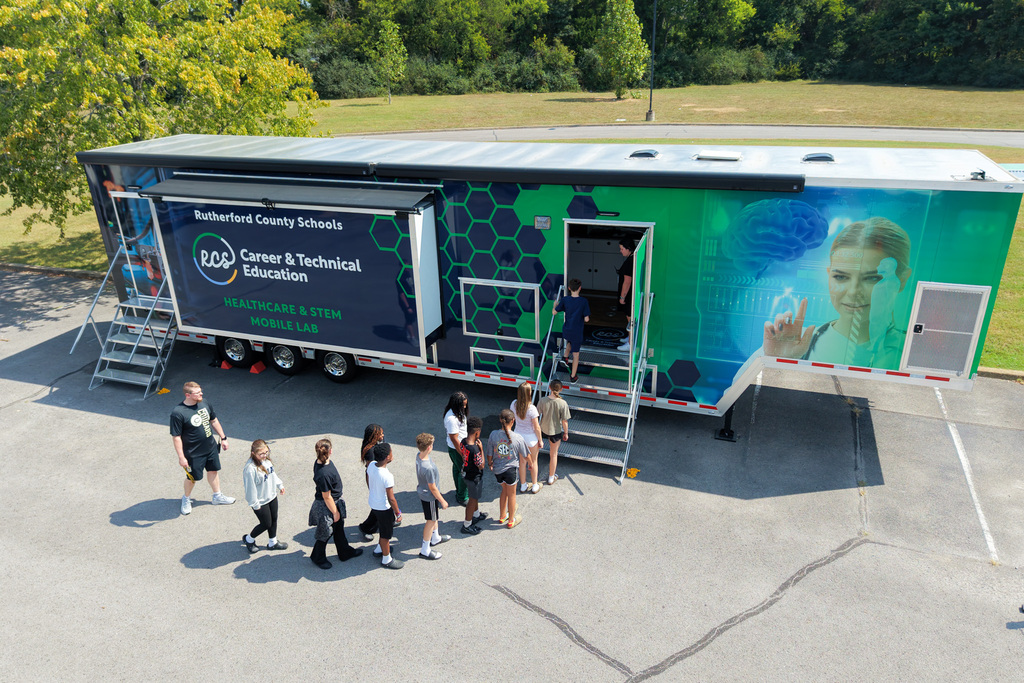 Group of children walking to a mobile education unit with an image of a female scientist.