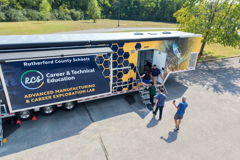 People entering a large trailer labeled "Career & Technical Education" and "Advanced Manufacturing & Career Exploration Lab."