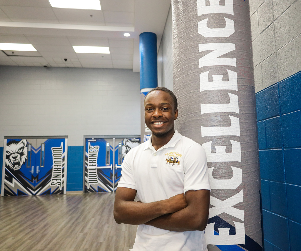Student standing by pillar that says, "Excellence."