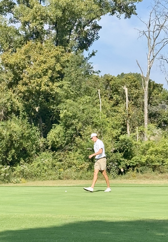 Golfer walks across the green