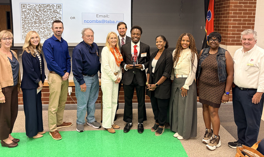 Student and faculty posing for picture with award